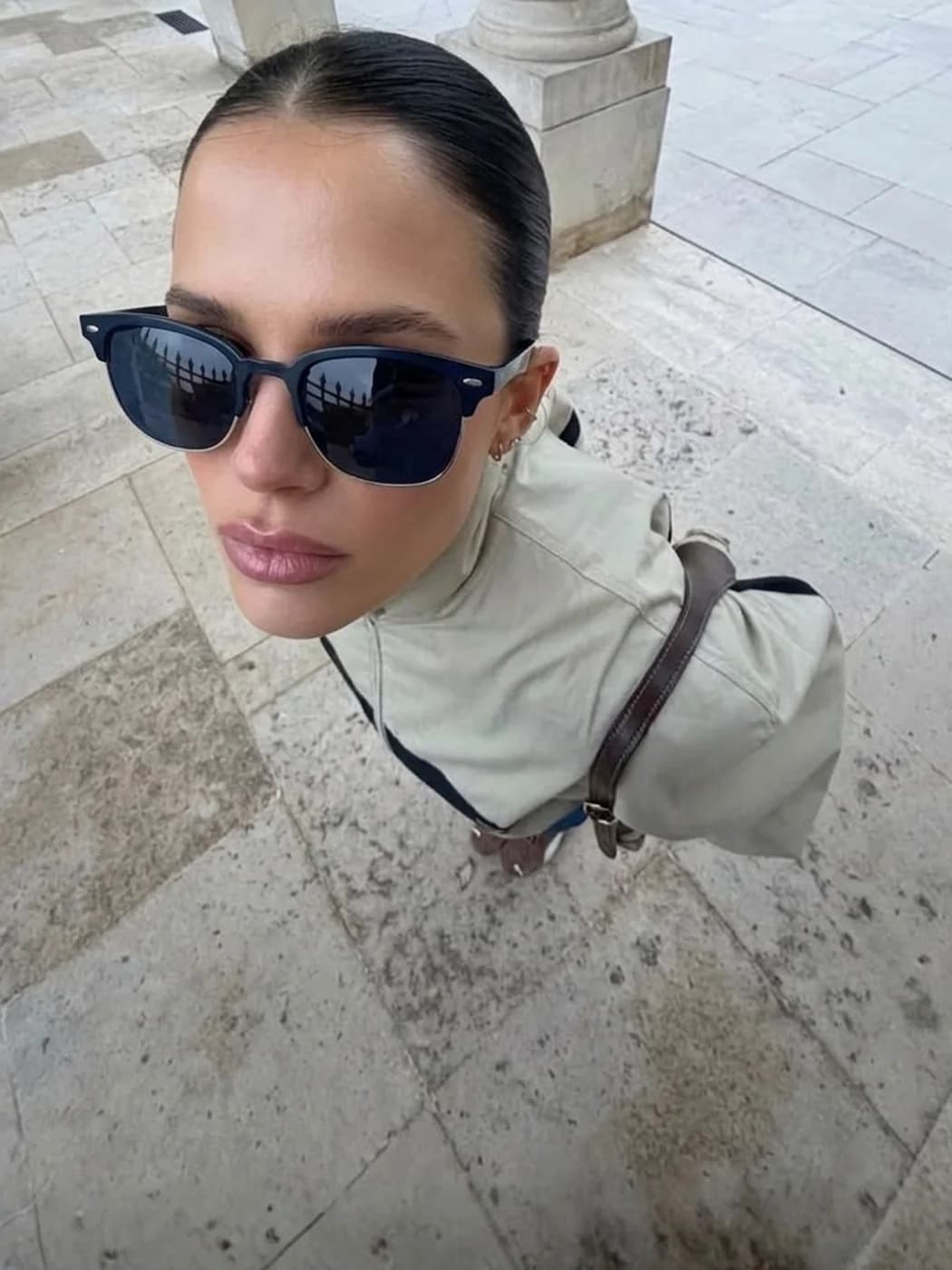 Retrato de estilo selfie de una mujer con anteojos de sol en un entorno urbano